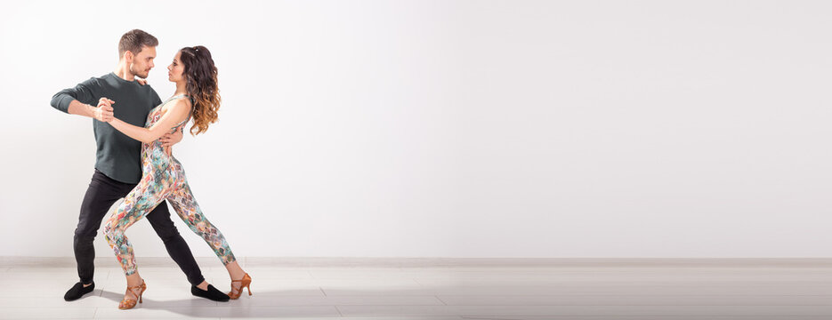 Banner social dance bachata salsa kizomba zouk tango concept - Man hugs woman while dancing over white background with copy space