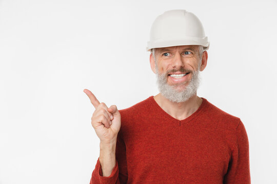 Closeup caucasian mature middle-aged man engineer architect construction worker builder in white hardhat pointing at copy space free space isolated in white background