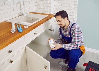 Male mechanic or plumber in uniform fix repair pipe work under sink in client home. Man repairman...