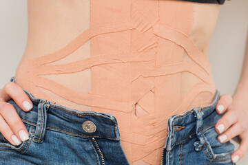 Kinesio medical tape on a woman's belly. The concept of fat loss and diastasis correction, recovery...