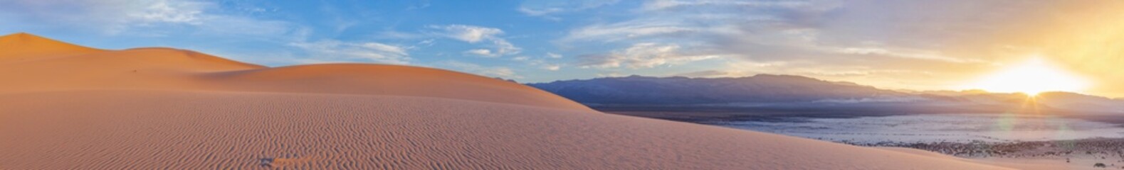 Eureka Dune at sunset is illuminated by a gentle pink light against a backdrop of dramatic clouds, Death Valley National Park, USA