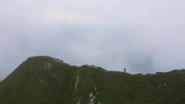 Group of people run on peak Augstmatthorn mountain, fog and mist weather, epic shot. Switzerland.  Swiss Alps. Drone footage 4K.