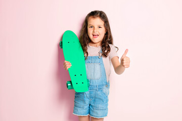 Funny little kid girl Hold skateboard on studio white background