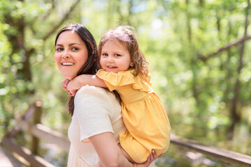 mother with his daughter having fun outside in forest