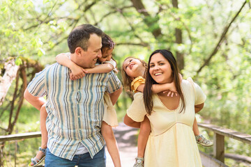 Naklejka premium Father and mother with the daughters having fun outside in forest