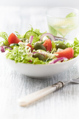 Salad with Green Olives, Tomatoes and Feta Cheese. Bright wooden background. Close up.