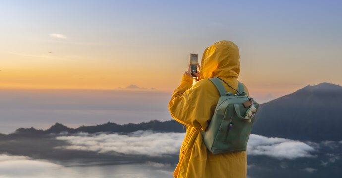 woman watching sunrise taking a photo