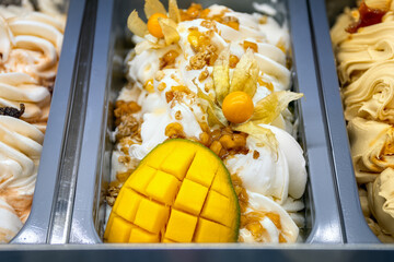 Mango ice cream with physalis. Various ice creams in trays in the ice cream shop top view.
