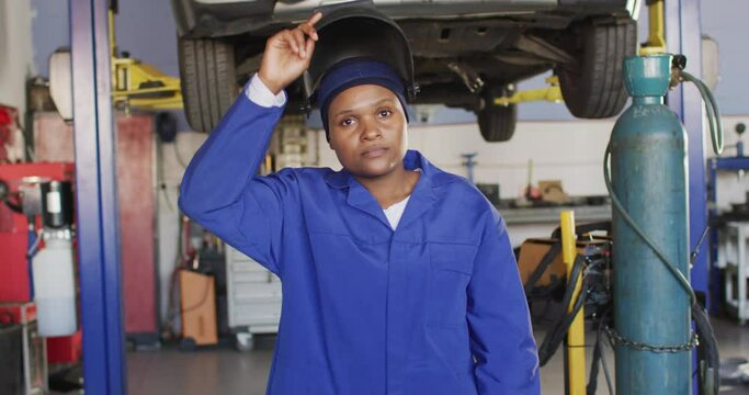 Video of african american female car mechanic, taking off welding mask