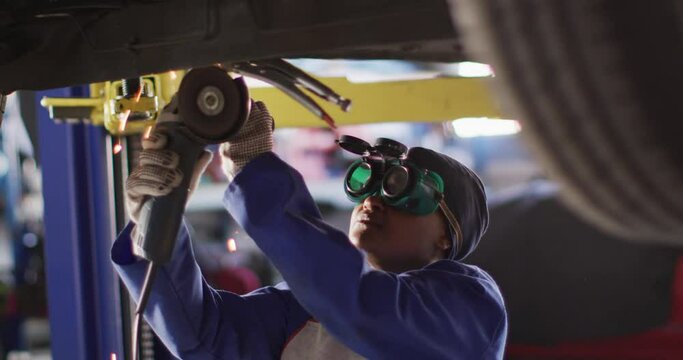 Video of afrcian american female car mechanic using grinder