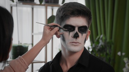 A young man is preparing makeup for Halloween. Create a Halloween look