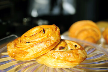 Cinnamon rolls pastry with small pieces of resins on  glass plate in the coffee shop