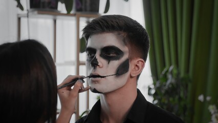 A young man is preparing makeup for Halloween. Create a Halloween look