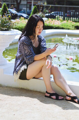 Portrait of young happy business woman relaxing, working in green park in city. Using phone. Selfie. Technology. Social media. Video call