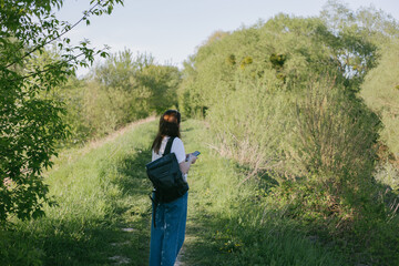 Fototapeta premium portrait of a young woman with a backpack and phone in nature