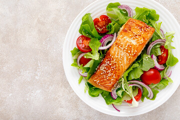 Grilled salmon fish fillet and fresh vegetable salad with tomato, red onion and lettuce
