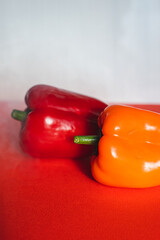 SWEET RED AND ORANGE PEPPERS ON A RED BACKGROUND