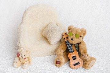 Shoot set up with sofa, teddy bear wearing sunglasses and guitar for newborn on white background....