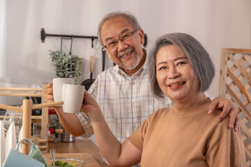 Two senior hold a white cup of coffee which a famous beverage to refresh. themselves in a kitchen at home.