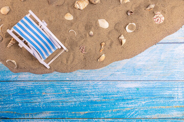 Sun lounger and seashells on the sand on a blue background