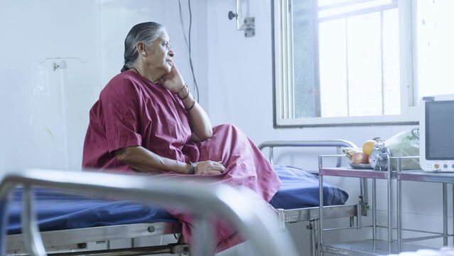 handheld shot of Senior sick women deep thinking while sitting on bed at hospital before surgery - concept of disease, worried and medicare.