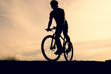 Naklejka na ściany i meble Silhouettes of mountain bikes and cyclists in the evening happily. Travel and fitness concept