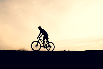 Naklejka na ściany i meble Silhouettes of mountain bikes and cyclists in the evening happily. Travel and fitness concept