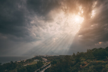 Majestic and dramatic sunlight beams through dense clouds at Konyaalti beach in Antalya, Turkey. Travel destinations backgrounds