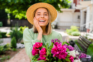 beautiful young woman in summer style outfit smiling happy walking with flowers in city street
