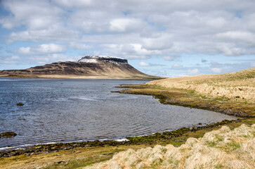 Landscape on the northcoast of Snaefellsnes peninsula, with beaches, grassy hills and a table mountain under a friendly sky