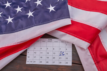 Fototapeta premium United states flag with calendar with marked june 14th. Top view flat lay.