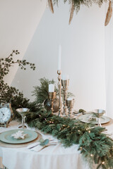 decorated New Year's table in light. New Year's festive table setting. Merry Christmas family dinner by candlelight. Gold. Beautiful table setting for Christmas dinner