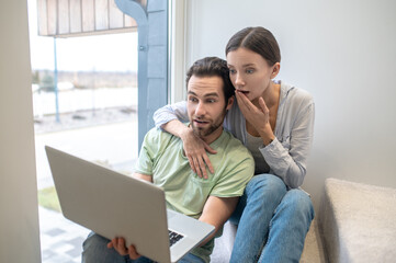 Man and woman looking inquiringly surprised at laptop