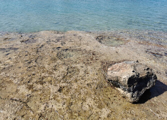 The coast of the Mediterranean Sea, clear water with reflections, through which you can see the stone bottom.