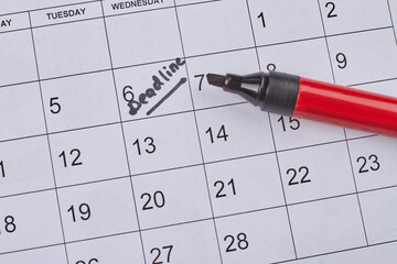 Deadline word written on the calendar by black marker top view. Black highlighter on the calendar.