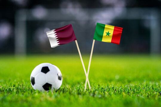 Qatar vs. Senegal, Al Thumama, Football match wallpaper, Handmade national flags and soccer ball on green grass. Football stadium in background. Black edit space.