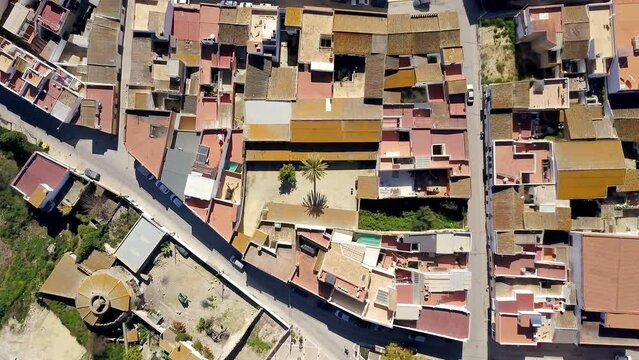 amazing drone wide angle overthe top shoot of a wonderful white town of Cadiz, Spain with its colored roofs and the green summer fields with vineyards and different green, yellow and red colors