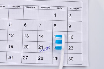 Close-up toothbrush on the calendar with marked dentist day. Top view flat lay.
