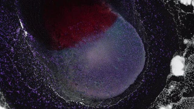 Dark purple black red colors ink and shiny particles macro. Fluid art