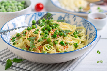 Spaghetti with zucchini and green peas.