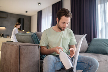 Man holding part of vacuum cleaner sitting on couch