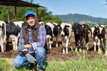 portrait of a farmer resting on green grass among cows