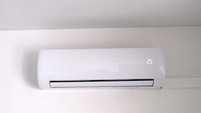 Turning on white air conditioner on white wall. Modern air conditioning technologies. Slow motion