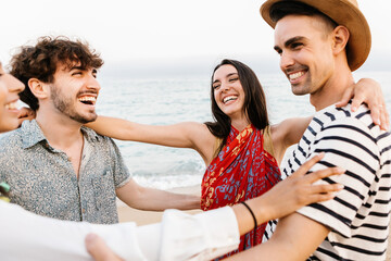Group of happy young friends laughing together while having fun on summer holidays at beach