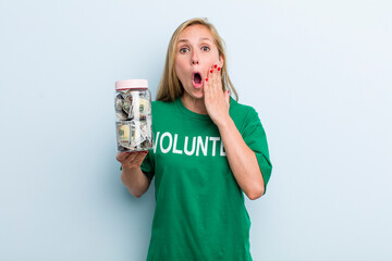 young adult blonde woman feeling shocked and scared. volunteer and donation concept