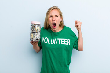 young adult blonde woman shouting aggressively with an angry expression. volunteer and donation...
