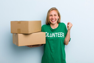 young adult blonde woman feeling shocked,laughing and celebrating success. volunteer and donation...
