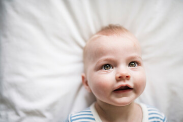 Adorable baby boy in white sunny bedroom in the morning at home