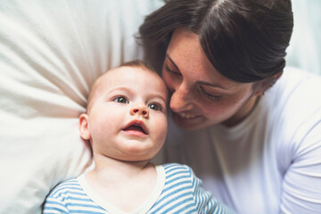 Mother and baby on white bed at home