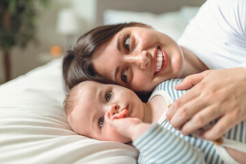 Mother and baby on white bed at home